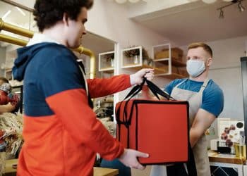 Repartidor entrega bolsa térmica de comida a trabajador en un restaurante, imagen de servicio a domicilio – Mundo Chido