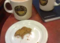 Taza de café con especias de calabaza junto a una galleta
