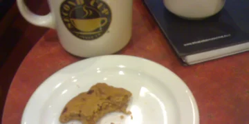 Taza de café con especias de calabaza junto a una galleta
