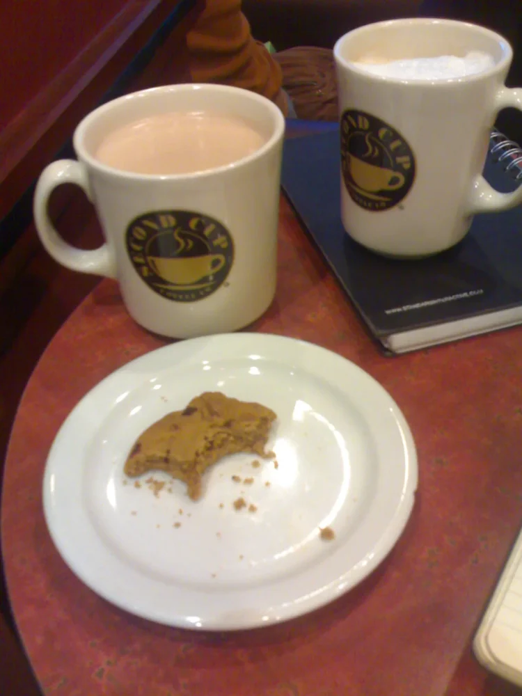 Taza de café con especias de calabaza junto a una galleta
