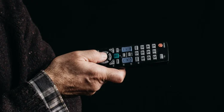 Persona viendo televisión en el sofá con mando a distancia