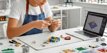 Una persona con delantal monta coloridos ladrillos de LEGO en un escritorio, rodeado de organizados contenedores de piezas de LEGO. Cerca, en un espacio de trabajo moderno y luminoso, hay un ordenador portátil con un modelo en 3D.