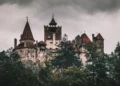 Castillo de Bran entre árboles bajo un cielo nublado