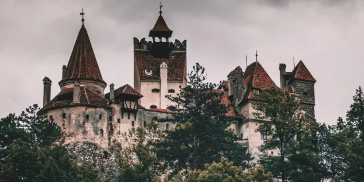 Castillo de Bran entre árboles bajo un cielo nublado