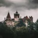Castillo de Bran entre árboles bajo un cielo nublado