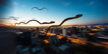 Imagen surrealista de serpientes voladoras sobre una ciudad al atardecer, con movimiento borroso en el fondo.