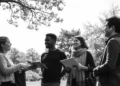 Grupo de jóvenes conversando al aire libre bajo un árbol en un parque, imagen en blanco y negro – Mundo Chido